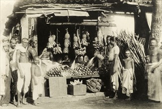 Ceylonian fruit stall. A group of Ceylonian men, women and children in traditional dress stand