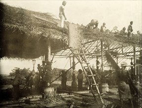 Thatching a roof for the royal visit. A team of Ceylonian men thatch the roof of a spectator stand