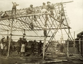 Building a spectator stand for the royal visit. A team of Ceylonian men construct the frame of a