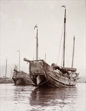 Junks moored at a Hong Kong harbour. Two Chinese junks are moored at a Hong Kong harbour with their