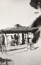 On watch at 'Pagoda Hill'. A Burmese man dressed in military uniform and a fez hat sits on a stool