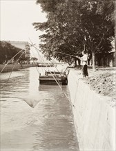 Fishing in Bowrington Canal. A Chinese fisherman raises his net from Bowrington Canal, pulling on a