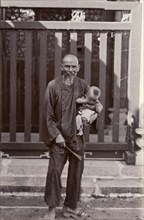 An elderly Cantonese man holds his great-grandson. Portrait of an elderly Cantonese man, holding