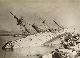HMS Phoenix capsized by a typhoon. HMS Phoenix, a British naval steamship, lies upturned in shallow