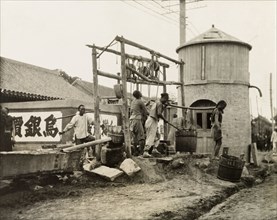 A hand-drawn street well in China. Two men collect water from a street well, carrying it away in a
