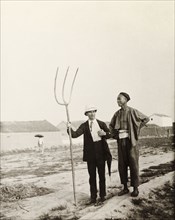 European man with Chinese farming tool. A European man, dressed in a suit and solatopi hat, holds a