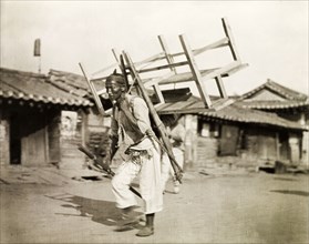A Korean labourer carries a bench. A Korean labourer carries a wooden bench strapped to his back