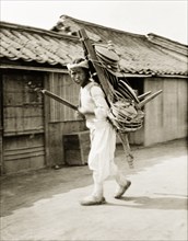 A Korean peddler boy. A Korean peddler boy carries his wares, probably crockery of some kind, on a