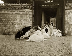 Korean women in traditional 'hanbok' dress. A group of Korean women and girls sit in the grounds of
