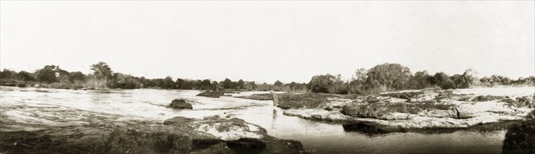 Rapids above Victoria Falls. Arthur Rhodes (brother of Cecil John Rhodes) paddles in the shallows