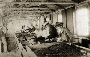 Sorting gravel for diamonds'. European workers at the De Beers diamond mine sift through trays of