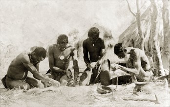 Tanners preparing a hide. Four tanners work on an animal hide that has been pegged to the ground,