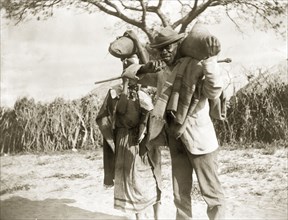 Couple carrying sacks. An African man and woman carry sacks along a rural road. Probably