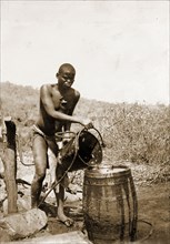 Collecting water at a village well. A Matabele (Ndebele) man pours water from a bucket into a