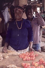 Preparing food at Bakau market. An African man and woman smile for the camera as they prepare food