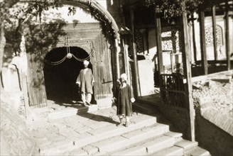 Turbaned men enter a mosque. Two Indian men stand on steps outside a doorway leading into a mosque.