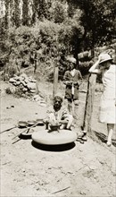 A potter in Srinagar. An Indian potter sits on the ground outdoors, shaping clay into a pot using a