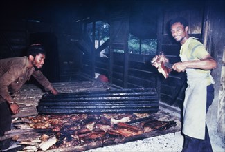 Preparing Jamaican pork jerk. An official Jamaican Tourist Board photograph features two men