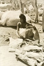 Eritrean woman setting up stall at camel market. An Eritrean woman unloads her goods, probably