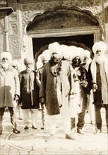 Sikh men at the Harimandir Sahib. A group of turbaned Sikh men stand in front of an ornate archway