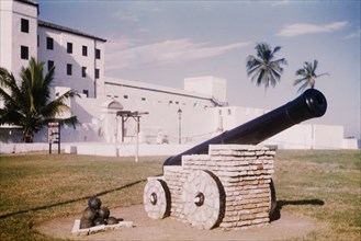 A cannon at Elmina Castle. A cannon and a heap of cannon balls are positioned as a monument in