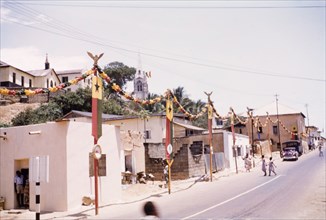 First anniversary of Ghanaian independence. A street in Cape Coast is decorated with flags and