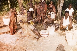 Ghanaian basketweavers. A group of craftsmen sit on the ground as they weave baskets outdoors.