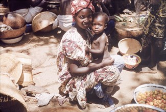 Mother and baby at a vegetable stall, Ghana. A mother and her baby daughter are pictured on a