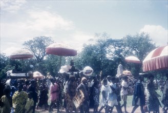 Procession at a Ngmayem festival. A procession of people passes through an open, grassy space at an