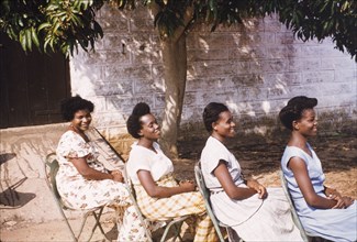 Hairstyles of four Ghanaian women. Four female Assistant Education Officers sit in a row in