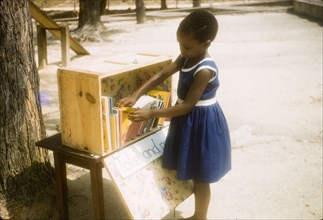Browsing books in a class library. A young girl browses through books in the class library at