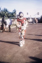 A performing masquerader. A costumed masquerader performs at an outdoor ceremony to celebrate Ghana