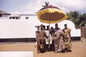 Ghanaian chief with his retinue. A Ghanaian chief poses with his retinue beneath a ceremonial