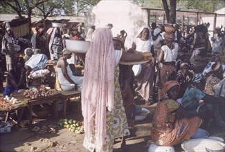 Dagomba woman at Tamale market. A woman wearing a traditional Dagomba veil carries containers of