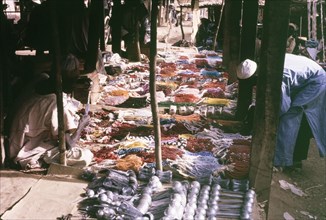 Beaded jewellery on a market stall. A customer bends down to inspect a huge selection of colourful