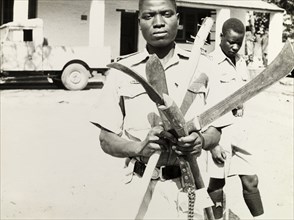 Confiscated weapons, Northern Rhodesia 1964. An officer of the Northern Rhodesia Police Force holds