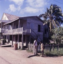 Wooden house in Belize. Two boys chat on a street corner outside a wooden, two-storey house in