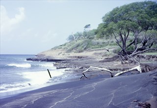 Black sand beach in Grenada. View across a beach of volcanic black sand. Grenada, circa 1975.