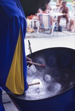 Barbadian musician playing steel drum. A Barbadian musician bows his head over a steel drum as he
