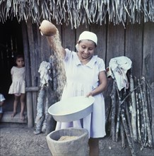 Separating the grain from the husk. A Ketchi woman pours rice from one bowl into another,