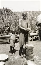 Preparing food outdoors, Kenya. A shy young child clings to his mother as she prepares food