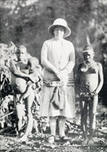 A British woman poses with "pigmy women". A British woman poses for a portrait in between two