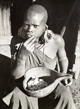 Kikuyu woman eating maize porridge. A Kikuyu woman sits on the ground eating a meal of maize