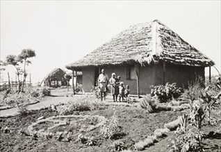 A Kikuyu family outside their home. A Kikuyu family pose in the garden outside their new,