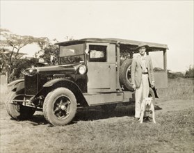 A Ford box-body car. A European man and his dog pose beside a Ford box-body car. Kenya, circa 1928.