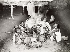 A Kikuyu family gather around a fire. A Kikuyu family gather around a smoky outdoor fire to eat