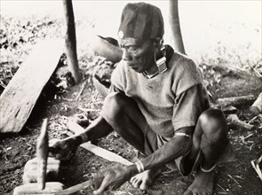 A Kikuyu metalsmith. A Kikuyu metalsmith hammers a knife blade into shape using an anvil in his