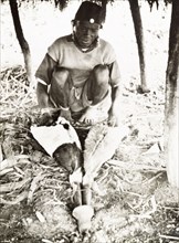 A Kikuyu metalsmith at work. A Kikuyu metalsmith operates a pair of goatskin bellows as he forges