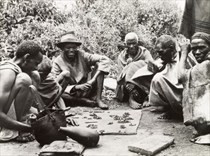 Telling fortunes by beans'. A group of Kikuyu men gather around to read their fortunes by