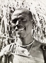 A Kikuyu witch doctor. Portrait of a smiling Kikuyu man, labelled in an original caption as a witch